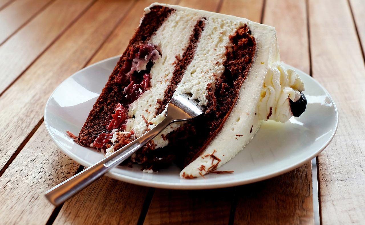 Slice of chocolate and cherry layer cake with cream filling on a plate